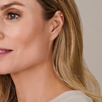 Close-up van gouden piercing oorbel met schroefdraad detail - City Juwelier